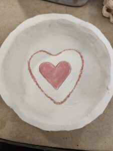 A white ceramic bowl decorated on the inside with red concentric hearts.