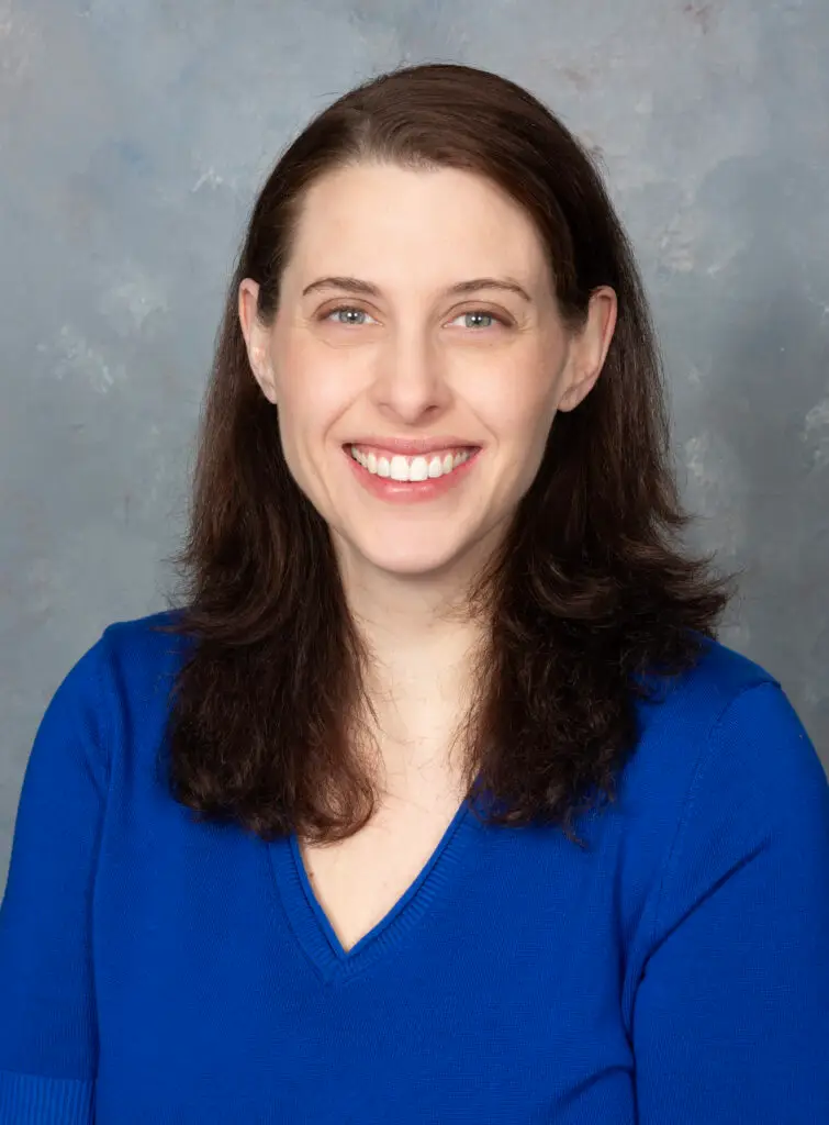 photo of Lori Starling, a white woman with long brown hair and blue eyes wearing a cobalt shirt in front of a grey backdrop.