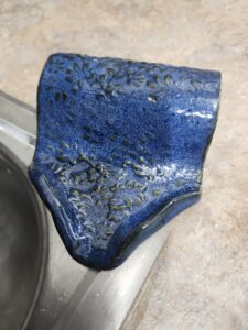 A deep blue ceramic soap dish sitting at the edge of a sink